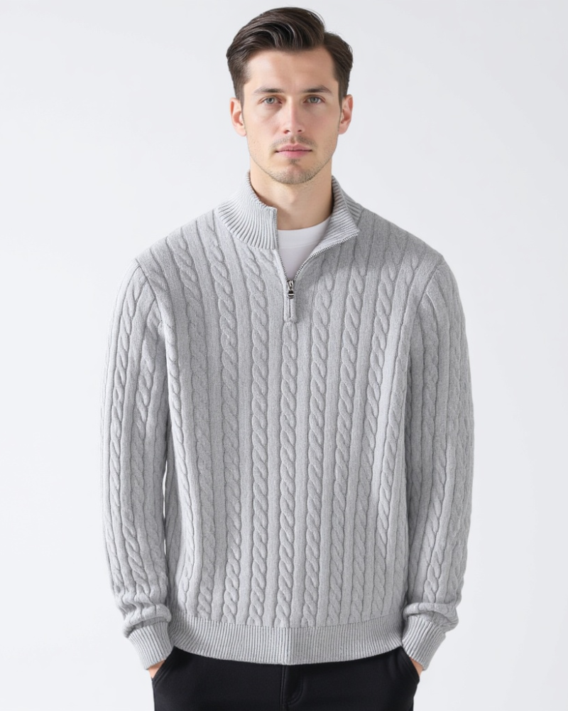 Mann trägt grauen Zopfmuster-Pullover mit Reißverschluss, modisch, elegant, Wintermode, Herrenbekleidung, stilvoller Look, weißer Hintergrund.