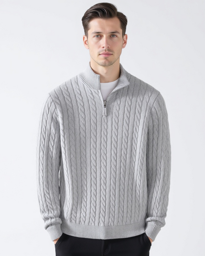 Mann trägt grauen Zopfmuster-Pullover mit Reißverschluss, modisch, elegant, Wintermode, Herrenbekleidung, stilvoller Look, weißer Hintergrund.