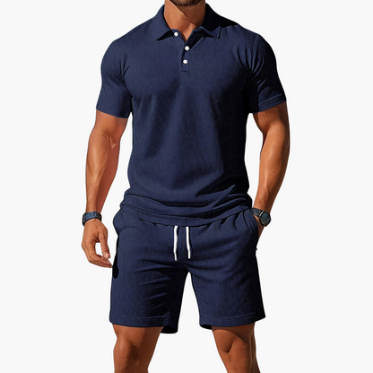 Mann in dunkelblauem Poloshirt und Shorts, sportlich-eleganter Look, Sommermode für Herren, Freizeitkleidung, stilvoll und modern.