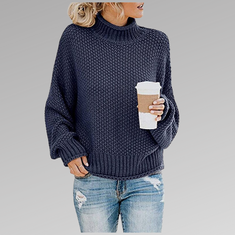 Frau in blauem Strickpullover mit Kaffeebecher, trägt zerrissene Jeans. Modetrend, Herbstmode, lässiger Stil, gemütlicher Look.