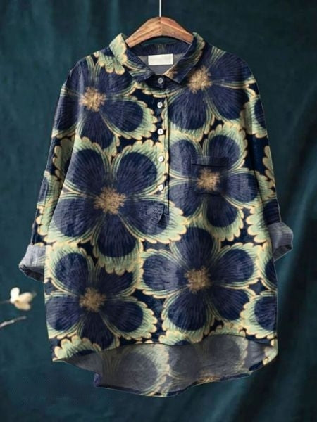 Damenbluse mit großem Blumenmuster, blau und beige, langärmlig, Knopfleiste, lässiger Stil, auf Holzkleiderbügel vor dunklem Hintergrund.