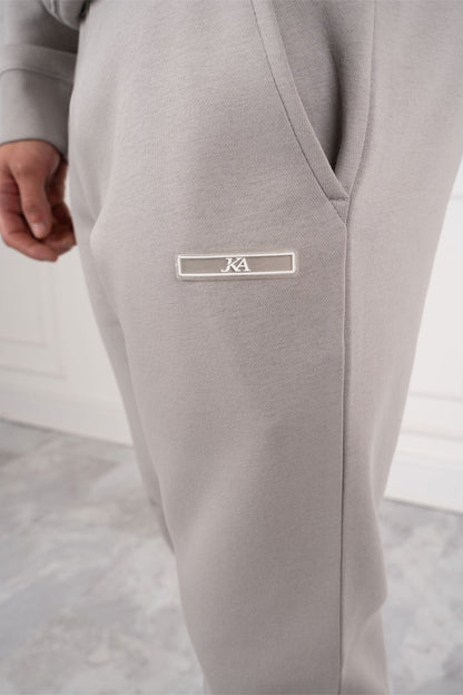Graue Jogginghose mit Logo-Emblem, Nahaufnahme. Bequeme Sportbekleidung, modernes Design, ideal für Freizeit und Fitness.