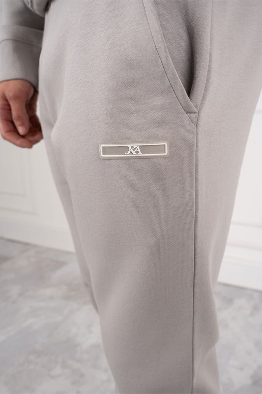 Graue Jogginghose mit Logo-Emblem, Nahaufnahme. Bequeme Sportbekleidung, modernes Design, ideal für Freizeit und Fitness.