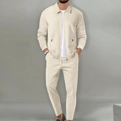 Eleganter Mann in beigem Anzug mit weißem T-Shirt und Armbanduhr, lässig posierend. Modetrend, Herrenmode, stilvoller Look.