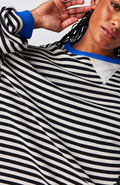 Schwarz-weiß gestreiftes Sweatshirt mit blauem Kragen, getragen von einer Person mit Dreadlocks. Modetrend, lässiger Stil, Unisex-Kleidung.