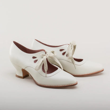 Weiße Vintage-Damenschuhe mit Absatz, Schnürung und dekorativen Ausschnitten, ideal für Retro-Mode und elegante Anlässe.