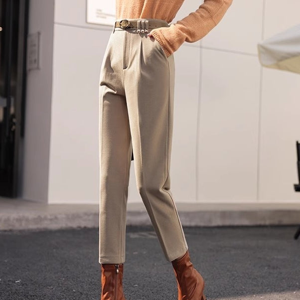 Elegante beige Hose mit hoher Taille, kombiniert mit einem orangefarbenen Pullover und braunen Stiefeletten. Modetrend Herbstmode Damenbekleidung.