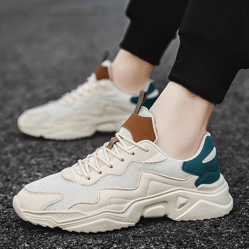 Beige Sneaker mit braunen und grünen Akzenten auf Asphalt. Modischer Herren-Sportschuh, atmungsaktives Mesh, ideal für Freizeit und Sport.