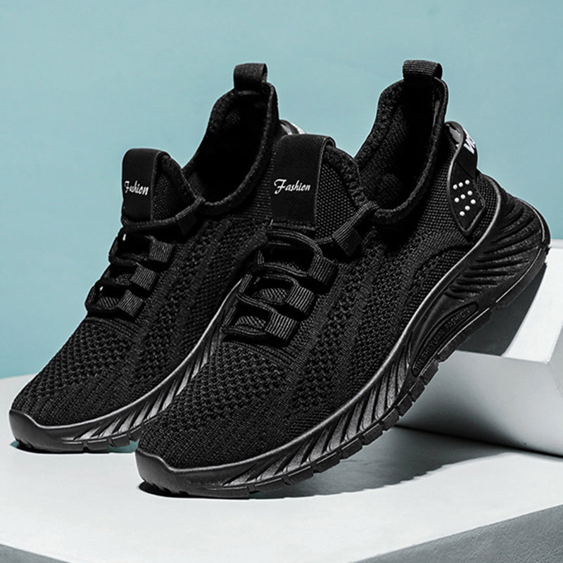 Schwarze Herren-Sneaker mit atmungsaktivem Mesh-Obermaterial, rutschfester Sohle und modernem Design auf grauem Hintergrund. Ideal für Sport und Freizeit.