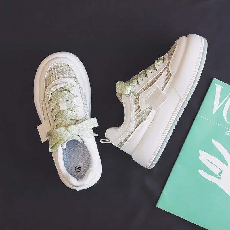 Grüne und weiße Sneaker auf schwarzem Hintergrund neben einem grünen Magazin. Modische Turnschuhe, moderne Sportschuhe, Streetwear.