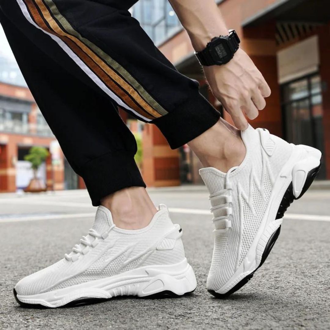 Weiße Sportschuhe für Herren auf städtischer Straße, getragen mit schwarzer Hose mit Streifen. Moderne Sneaker, ideal für Laufen und Freizeit.