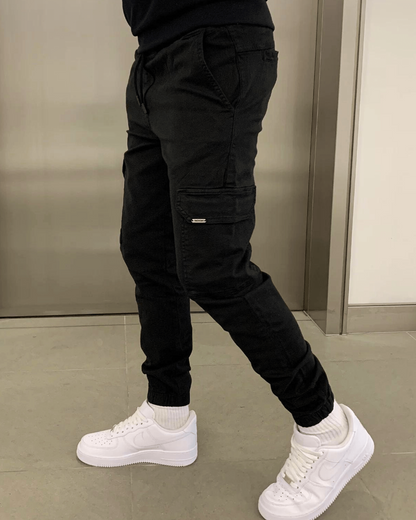 Schwarze Cargohose mit Seitentaschen, kombiniert mit weißen Sneakers. Moderne Herrenmode, urbaner Stil, lässiges Outfit für den Alltag.