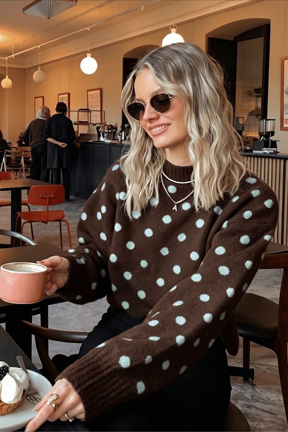 Brauner Damen-Strickpullover mit weissem Punktmuster auf hellem Hintergrund