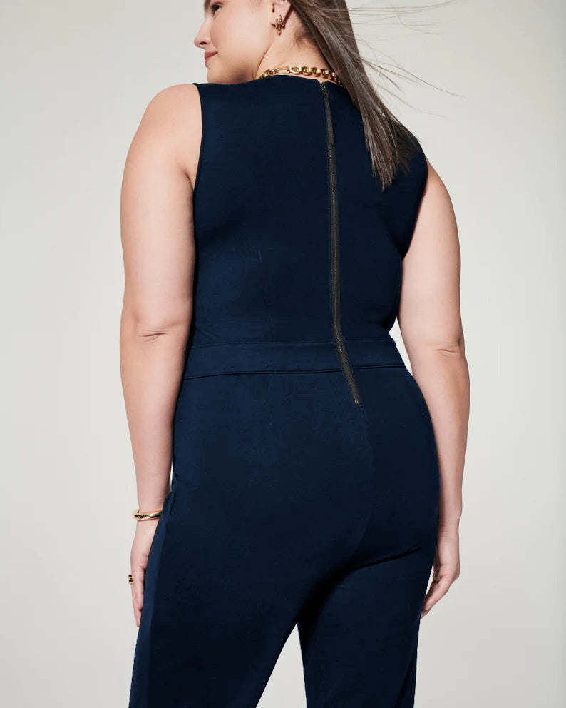 Frau in dunkelblauem ärmellosen Jumpsuit mit Reißverschluss am Rücken, goldener Kette und Armband. Mode für Damen, elegante Freizeitkleidung.