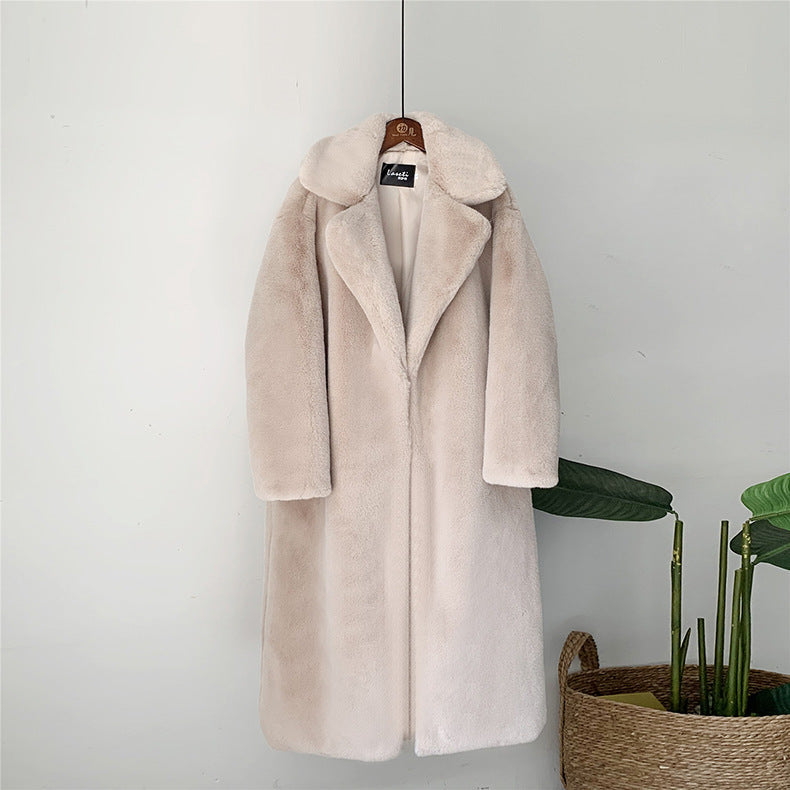 Beiger Kunstpelzmantel, lang, mit Reverskragen, an Holzbügel hängend. Elegante Wintermode, stilvoll und warm, ideal für kalte Tage.