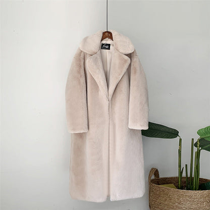 Beiger Kunstpelzmantel, lang, mit Reverskragen, an Holzbügel hängend. Elegante Wintermode, stilvoll und warm, ideal für kalte Tage.