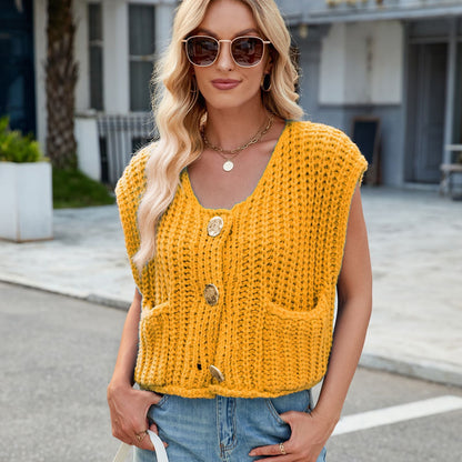 Frau mit blonder Welle, Sonnenbrille, gelber Strickweste mit Knöpfen und Taschen, Jeans, steht draußen. Modetrend, Sommeroutfit, lässiger Stil.