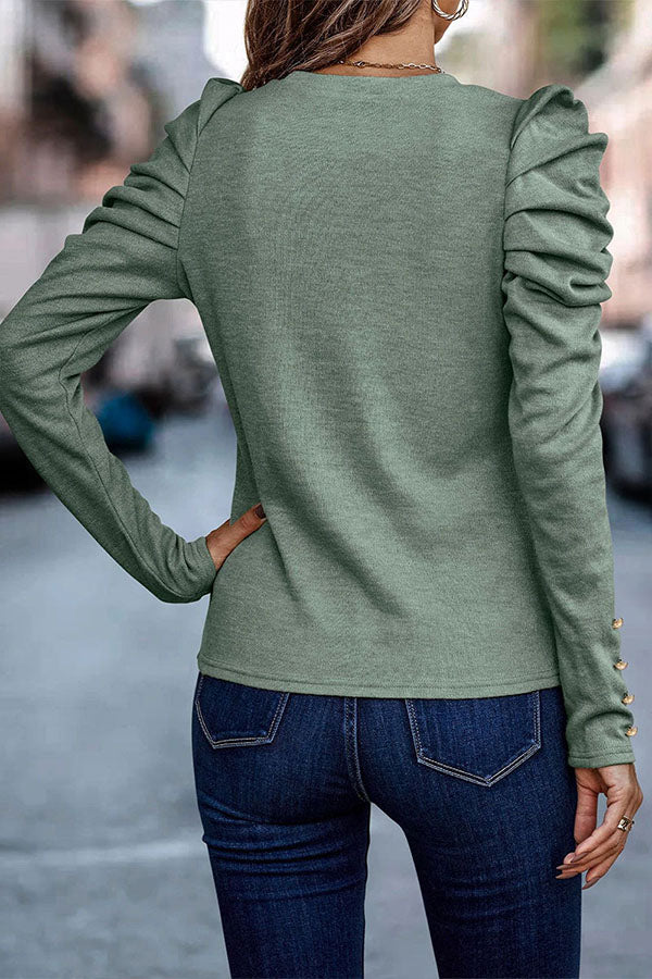 Frau in grüner Langarmbluse mit Rüschenärmeln und blauen Jeans auf Stadtstraße. Modetrend, Damenmode, Freizeitlook.