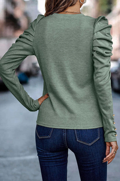 Frau in grüner Langarmbluse mit Rüschenärmeln und blauen Jeans auf Stadtstraße. Modetrend, Damenmode, Freizeitlook.