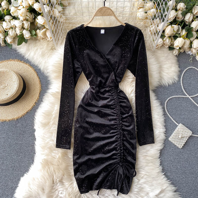 Schwarzes, glitzerndes Wickelkleid mit Raffung, umgeben von weißen Rosen, Strohhut und Perlenhandtasche auf flauschigem Teppich. Elegantes Abendoutfit.