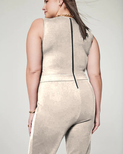 Frau in eleganter, beigefarbener ärmelloser Jumpsuit mit Reißverschluss hinten, goldener Kette und Armband. Mode, Damenbekleidung, Jumpsuit-Trend.