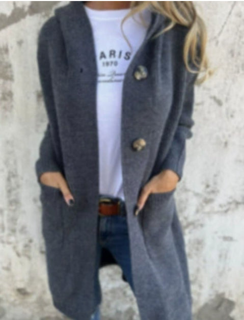 Frau in grauem Strickmantel mit Kapuze, trägt weißes Paris-T-Shirt und Jeans. Modischer Herbst-Look, lässig und stilvoll.