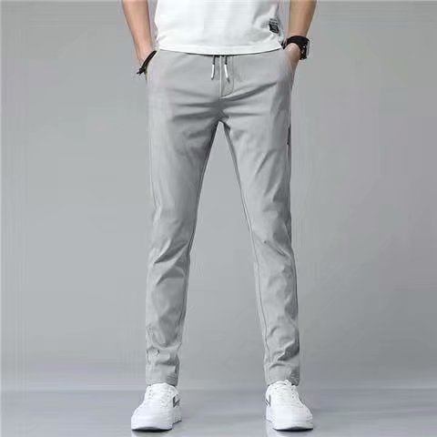 Graue Jogginghose für Herren, modern und bequem, mit Kordelzug und Taschen, kombiniert mit weißen Sneakers. Ideal für Freizeit und Sport.