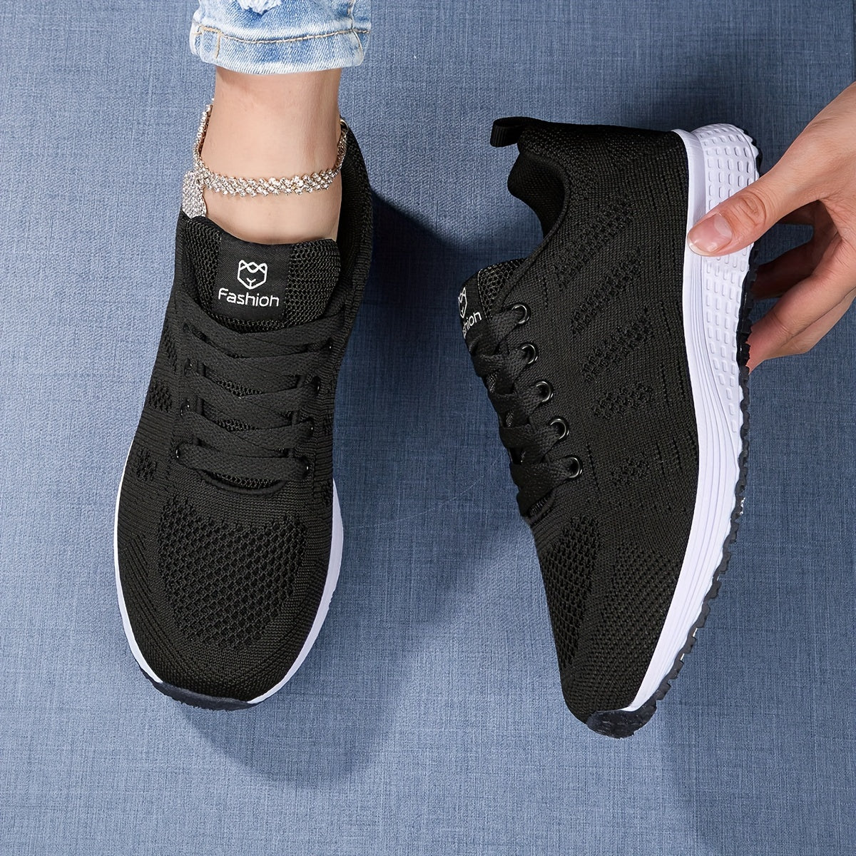 Schwarze Damen-Sneaker mit weißer Sohle auf blauem Hintergrund, modisches Design, bequeme Sportschuhe, ideal für Freizeit und Sport.