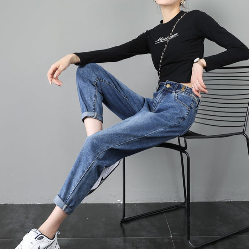 Dame in schwarzem Langarmshirt und blauer Jeans sitzt auf Stuhl. Modetrend, lässiger Stil, Streetwear, Damenmode, Freizeitlook.