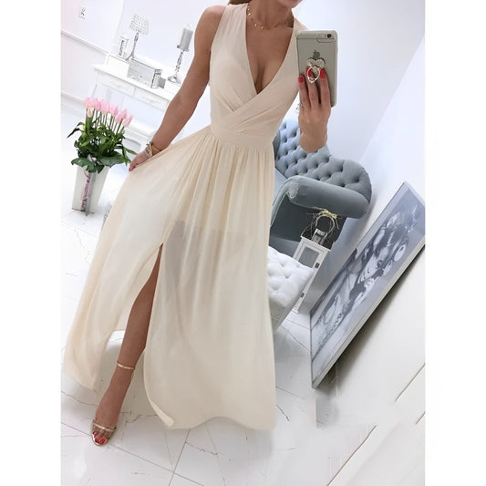 Frau in elegantem, cremefarbenem Abendkleid mit Beinschlitz, posiert vor Spiegel. Moderne Einrichtung, Blumen und Kunst im Hintergrund.