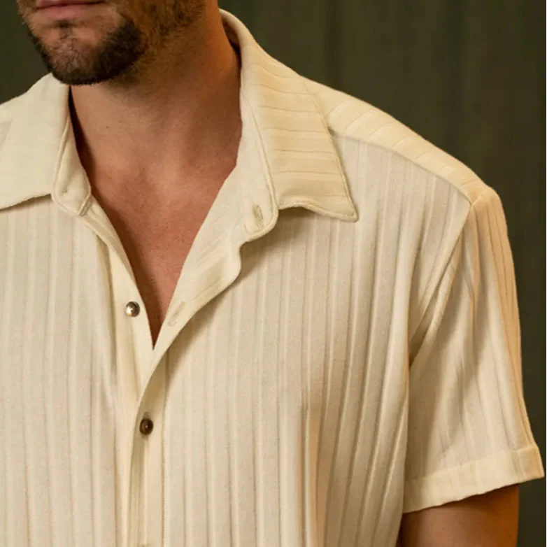 Mann in cremefarbenem, kurzärmligem Hemd mit Kragen und Knopfleiste. Modetrend, Herrenbekleidung, Sommerlook, eleganter Stil.