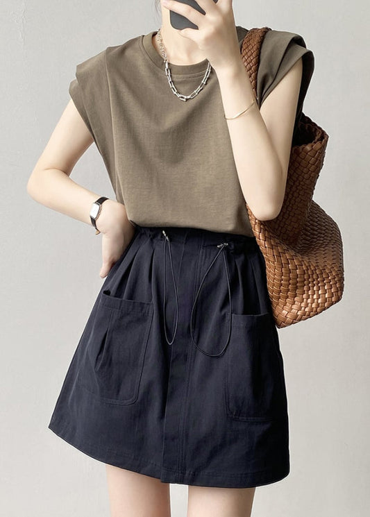 Frau in lässigem Outfit mit olivgrünem T-Shirt, schwarzem Rock und brauner Flechttasche. Modetrends, Damenmode, Sommerlook.