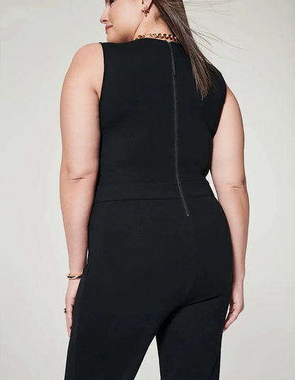 Frau in schwarzem ärmellosen Jumpsuit mit Reißverschluss hinten, goldene Halskette und Armband, modische Damenbekleidung, Rückansicht.