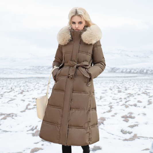 Frau in braunem Daunenmantel mit Fellkragen steht im verschneiten Winterlandschaft. Elegante Wintermode, warme Damenbekleidung, Outdoor-Stil.