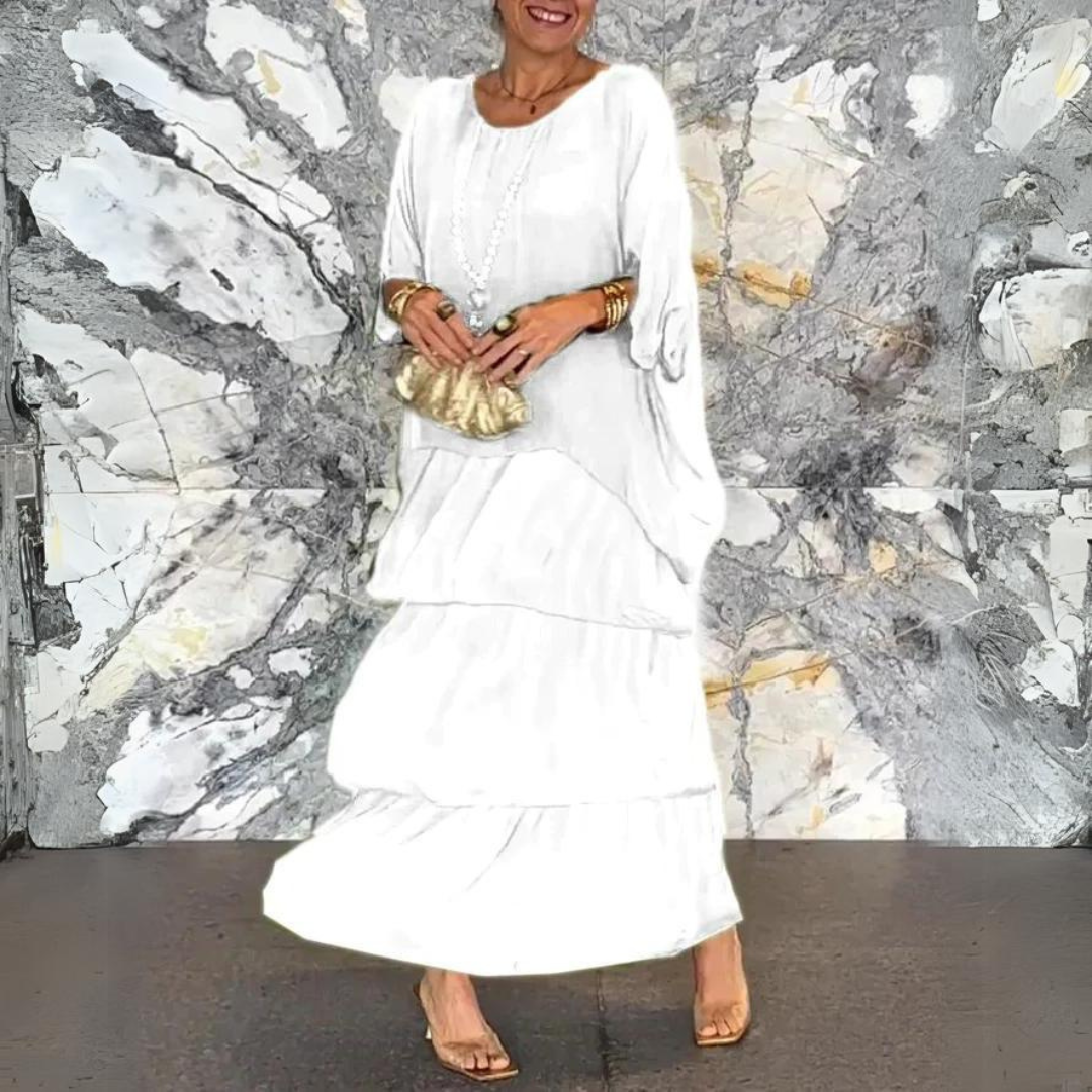 Elegante Frau in weißem Maxikleid mit goldener Clutch vor marmorierter Wand. Mode, Abendkleid, stilvoll, Damenmode, Accessoires.