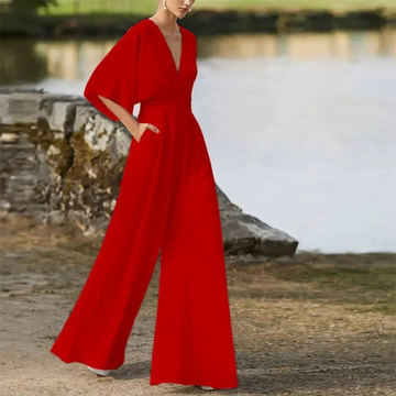 Rote Damen-Jumpsuit mit weitem Bein und tiefem V-Ausschnitt, elegantes Design, modische Abendmode, Outdoor-Hintergrund.