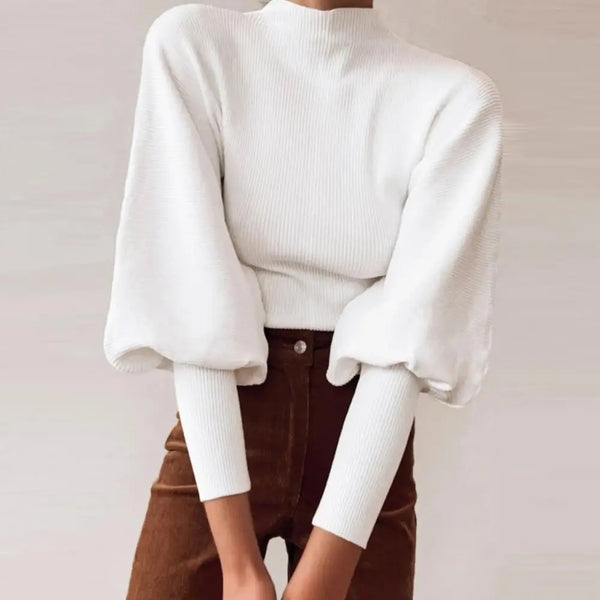 Weiße Strickbluse mit voluminösen Ärmeln, kombiniert mit brauner Hose. Modetrend, eleganter Look, Damenmode, Herbstoutfit.