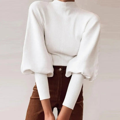 Weiße Strickbluse mit voluminösen Ärmeln, kombiniert mit brauner Hose. Modetrend, eleganter Look, Damenmode, Herbstoutfit.