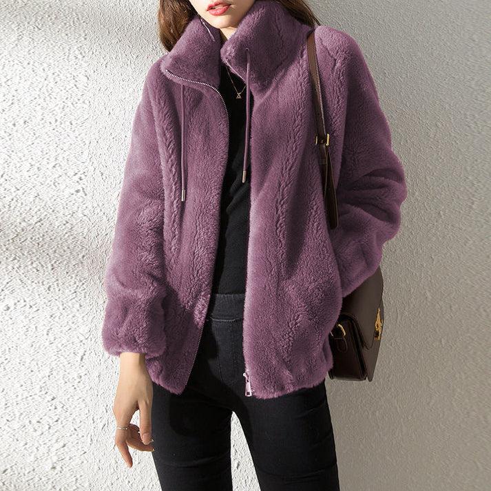 Frau in lila Kunstpelzjacke, schwarze Hose und Tasche. Modetrend Herbst/Winter, stilvolle Damenbekleidung, warme Jacke für kalte Tage.