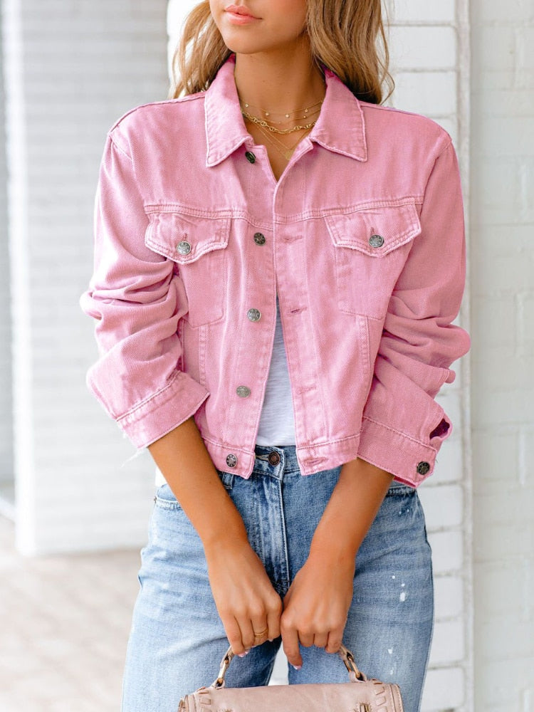 Frau in rosa Jeansjacke und blauer Jeans, hält eine beige Handtasche. Modetrend, lässiger Stil, Damenmode, Frühlingsoutfit.