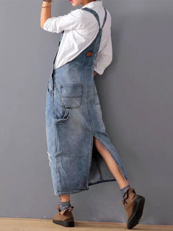 Frau in langem, blauem Jeanskleid mit weißen Hemd und braunen Schuhen vor grauer Wand. Modetrend, lässiger Stil, Denim-Look.