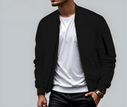 Mann in schwarzer Bomberjacke und weißem T-Shirt, trägt eine Armbanduhr, vor grauem Hintergrund. Modetrend, Herrenbekleidung, lässiger Stil.