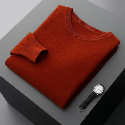 Roter Pullover aus Kaschmir auf grauem Tisch, daneben eine elegante Armbanduhr. Hochwertige Mode, luxuriöse Materialien, stilvolle Accessoires.