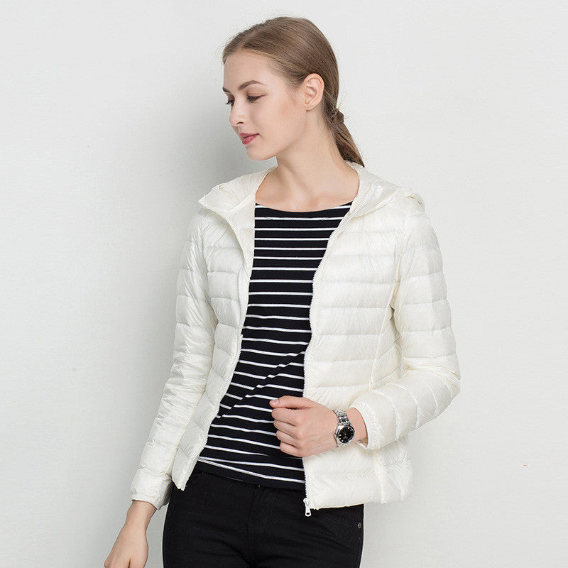 Frau in weißer Daunenjacke, gestreiftem Shirt und schwarzer Hose. Modetrend, Damenbekleidung, Winterjacke, stilvoll, lässig.