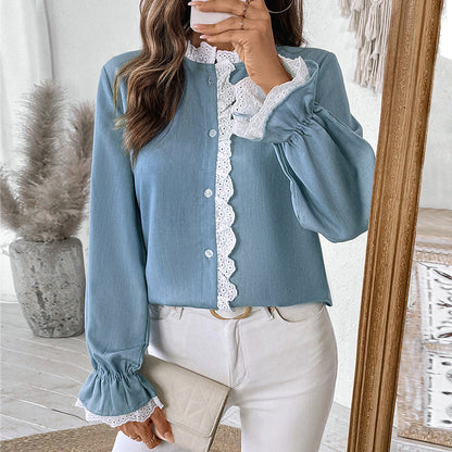 Frau in blauer Bluse mit Spitzenbesatz, hält eine cremefarbene Clutch. Modisches Outfit, eleganter Stil, perfekte Wahl für den Frühling.