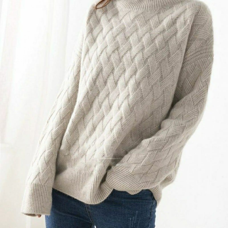 Beiger Strickpullover mit Zopfmuster, lässig getragen, kombiniert mit blauer Jeans. Perfekt für Herbstmode und gemütliche Winteroutfits.