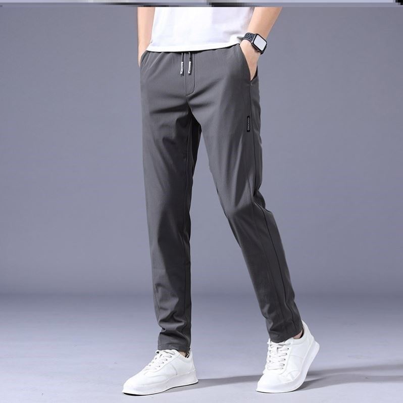 Graue Jogginghose für Herren, modern und bequem, kombiniert mit weißen Sneakers. Ideal für Sport und Freizeit. Hochwertige Sportbekleidung.