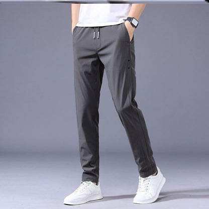 Graue Jogginghose für Herren, modern und bequem, kombiniert mit weißen Sneakers. Ideal für Sport und Freizeit. Hochwertige Sportbekleidung.