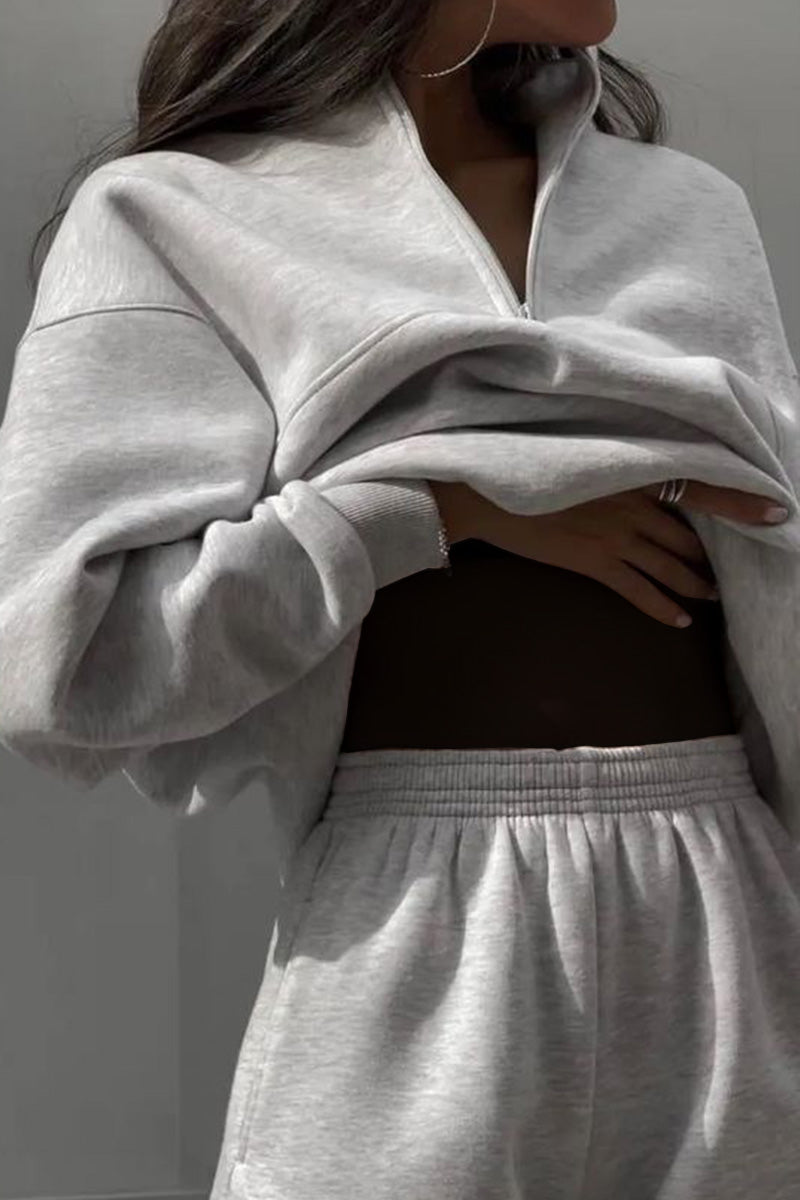 Frau in grauem Trainingsanzug, zeigt sportliche Mode. Bequemer Hoodie und Jogginghose, lässiger Stil, Freizeitkleidung, Trend 2023.