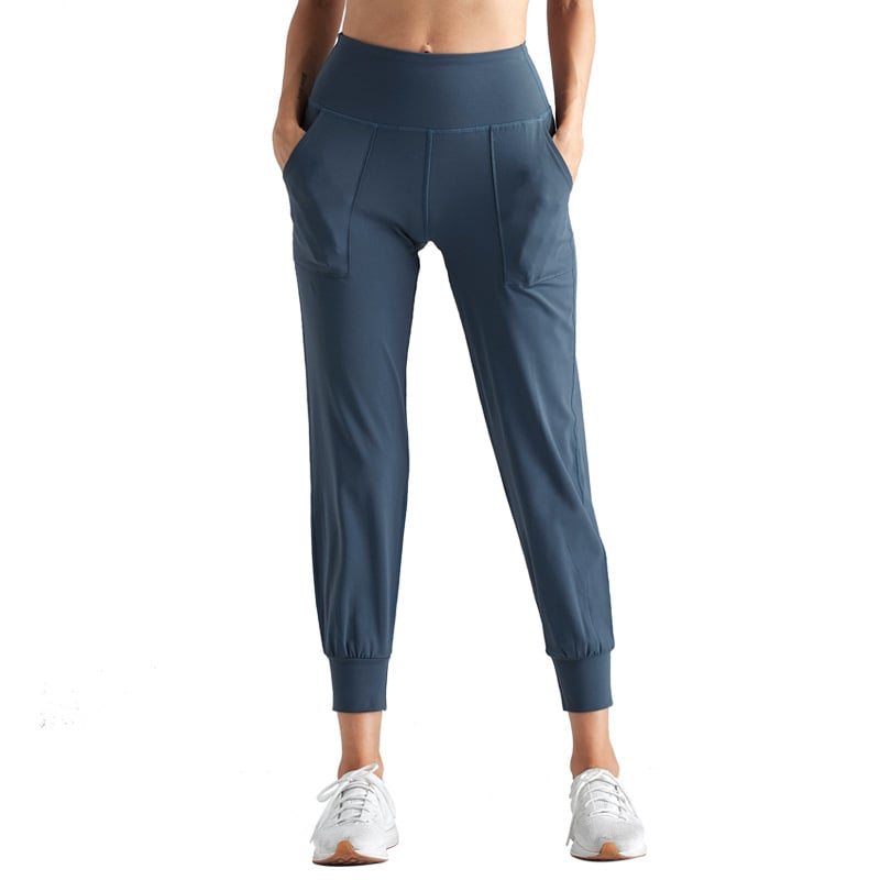 Damen Jogginghose in Blau, hoher Bund, seitliche Taschen, sportlich, bequem, ideal für Fitness und Freizeit, kombiniert mit weißen Sneakers.